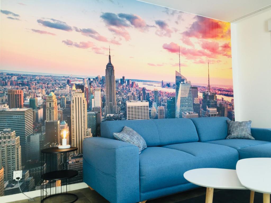 - un canapé bleu dans une chambre avec vue sur la ville dans l'établissement Magnifique T3 en plein coeur de Lorient, dernier étage avec balcon terrasse, à Lorient