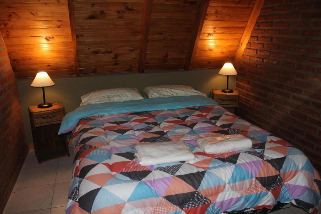 1 dormitorio con 1 cama con 2 lámparas en las mesas en Cabañas :Doña María Nuñez en Gualeguaychú