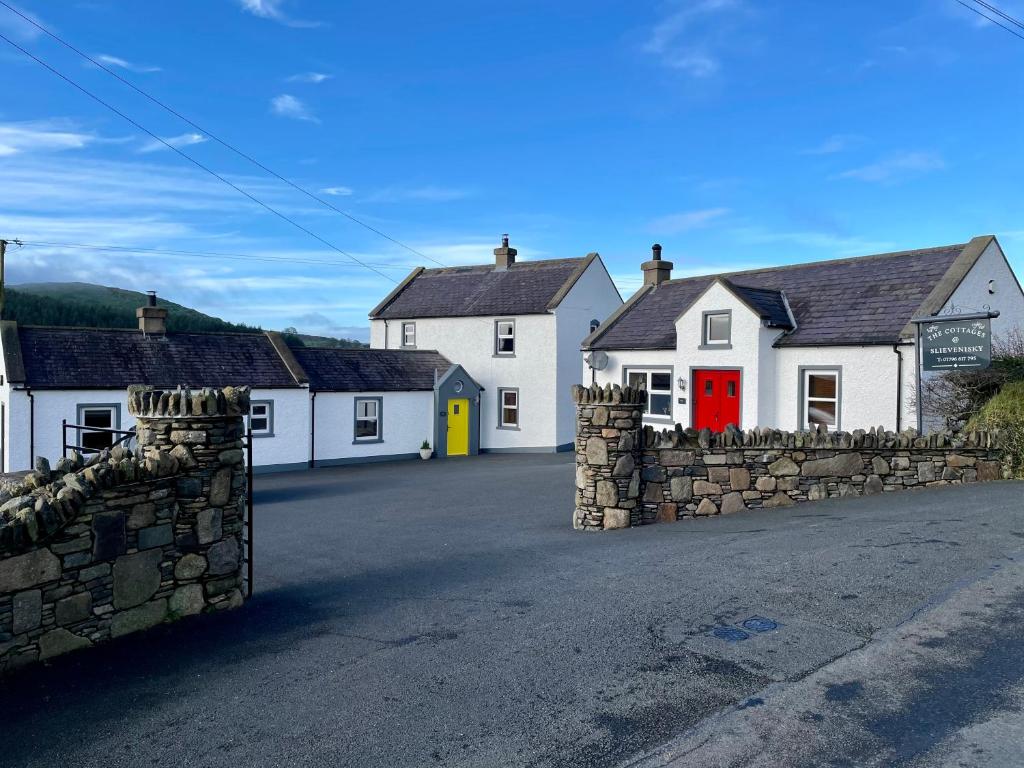 ein Dorf mit weißen Häusern mit einer roten Tür in der Unterkunft The Cottages @ Slievenisky in Ballyward