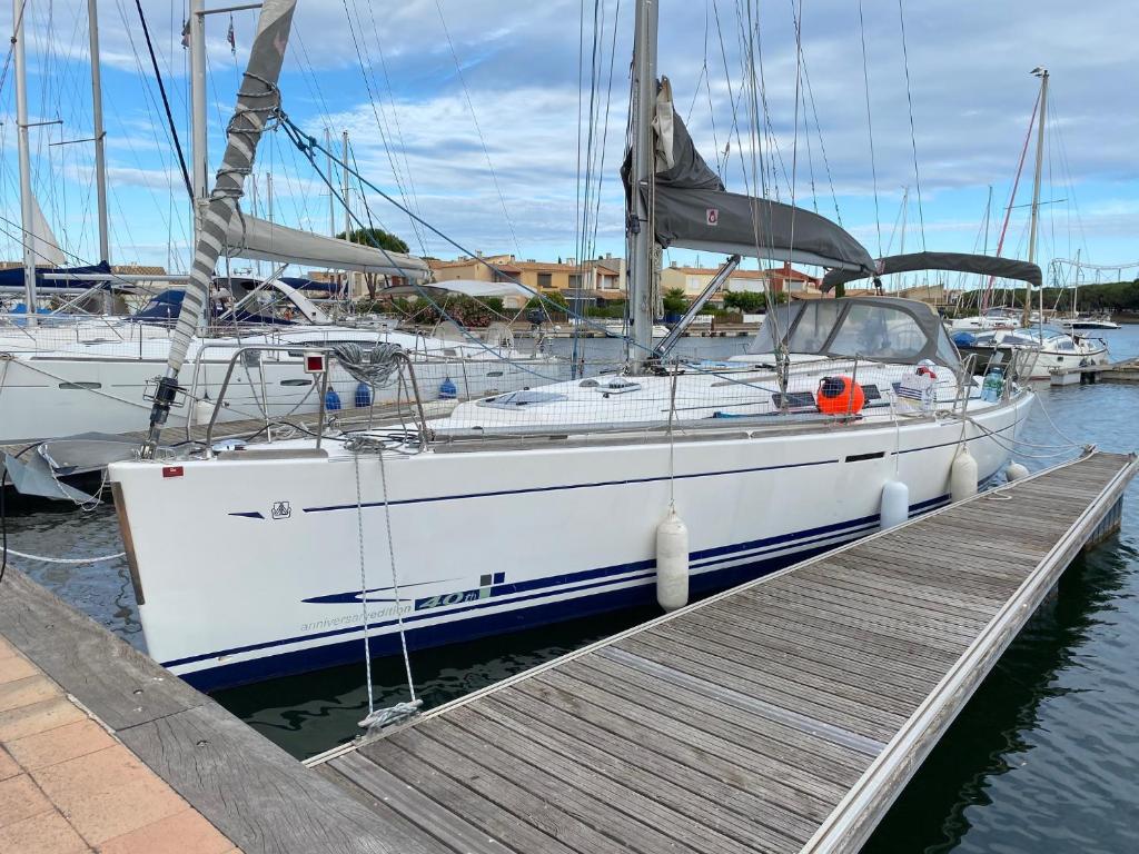 a white boat is docked at a dock at SUPERBE VOILIER CAP AGDE avec parking gratuit sur place in Cap d'Agde