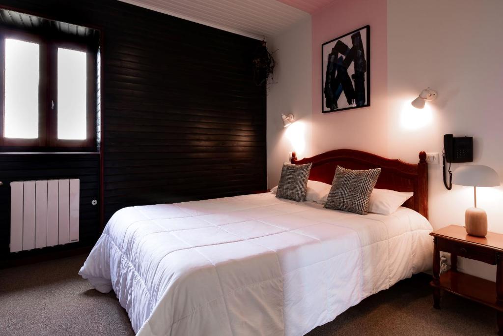 sypialnia z dużym białym łóżkiem z czarnym zagłówkiem w obiekcie Hôtel le Cantou 354 w mieście Loubressac