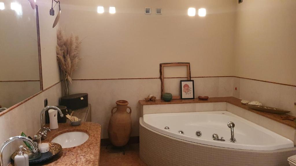 ein Badezimmer mit einer großen Badewanne und einem Waschbecken in der Unterkunft Glicine & more Forlì in Forlì