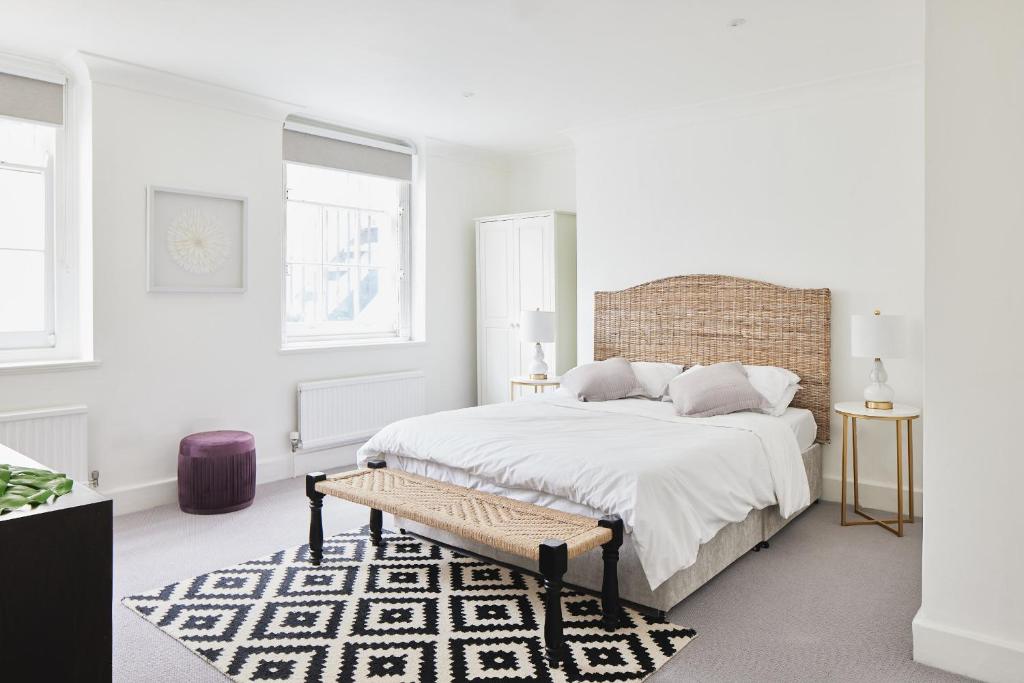 a white bedroom with a large bed and a bench at Luxury 1-bedroom apartment in Marylebone in London