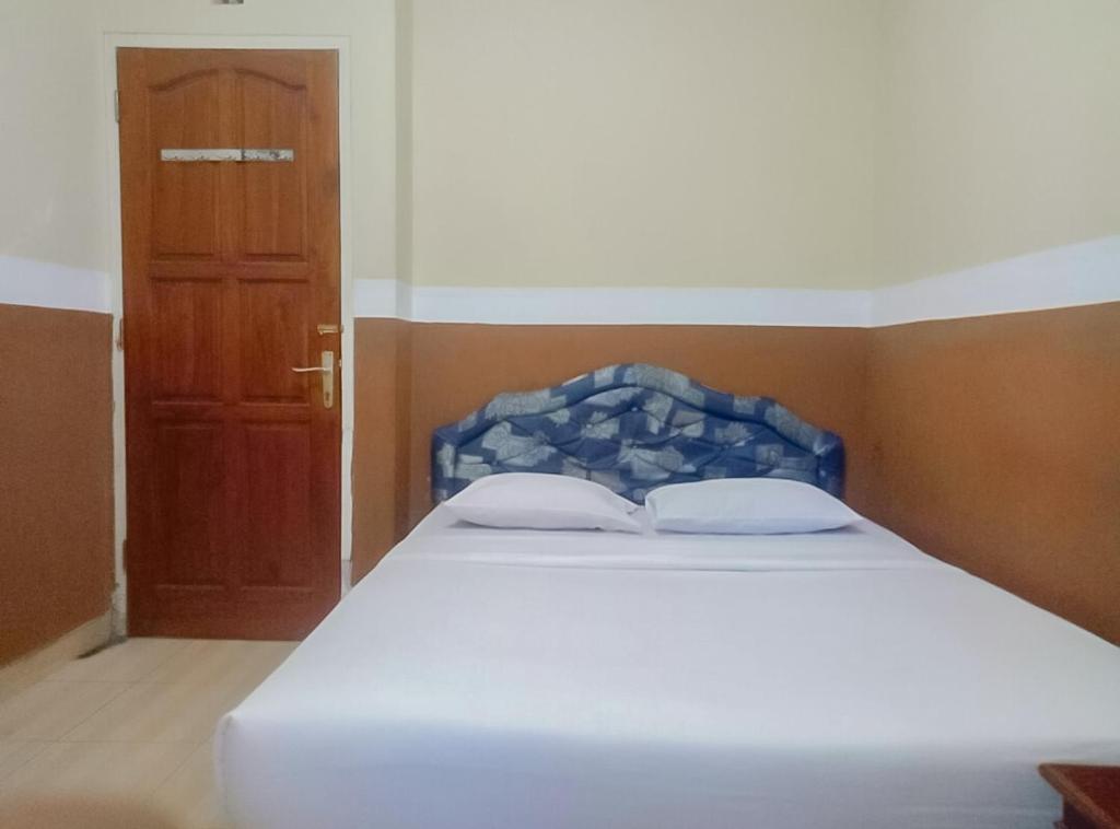 un letto con due cuscini in una stanza con una porta di RedDoorz Plus At Grand Yustik Sukabumi a Sukabumi