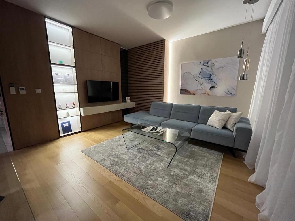 un salon avec un canapé bleu et une télévision dans l'établissement Exclusive BL apartments, à Banja Luka
