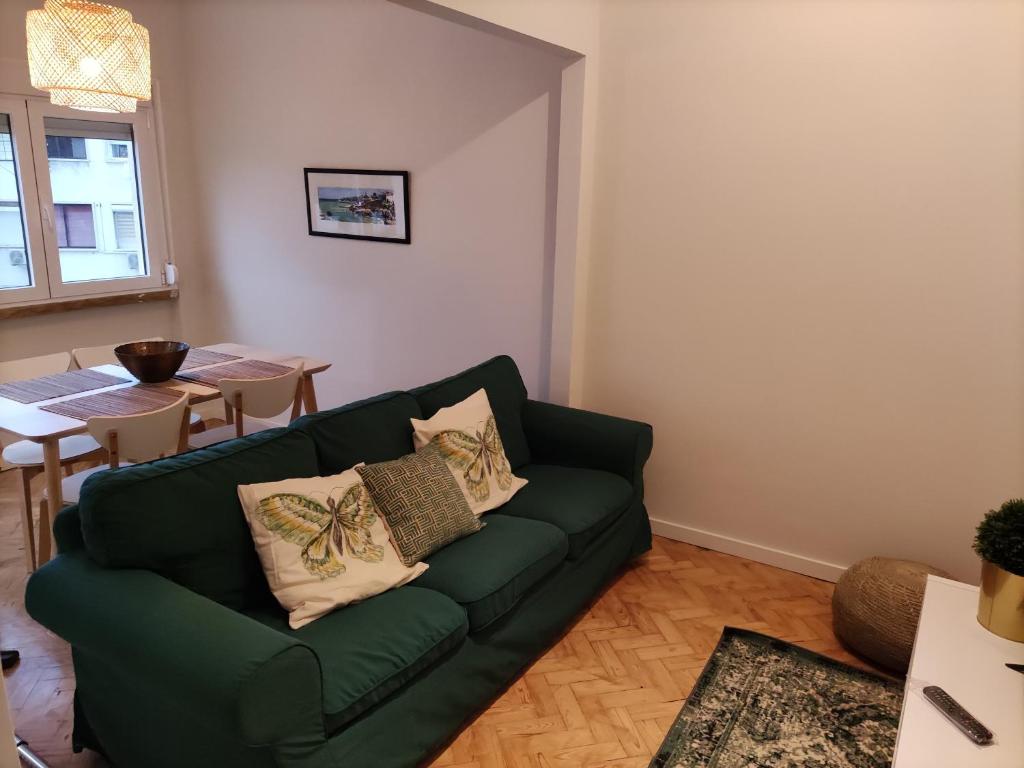 ein Wohnzimmer mit einem grünen Sofa und einem Tisch in der Unterkunft Memoria 49 - 21 in Lissabon