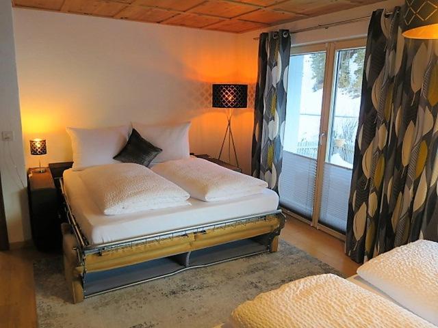 a bedroom with a bed with white pillows and a window at Chasa Max in Samnaun