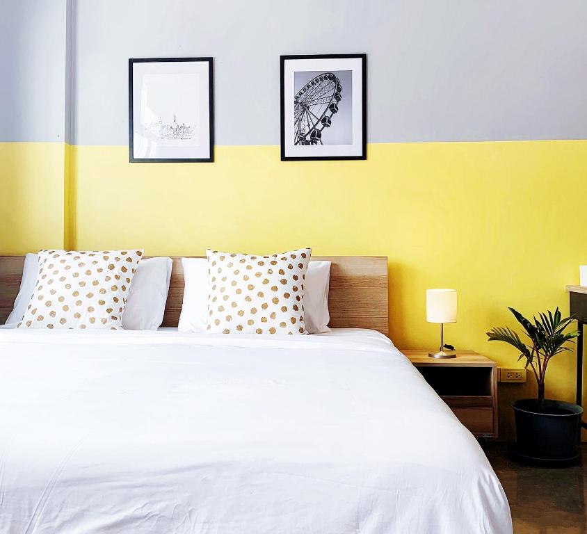 una camera da letto con un letto bianco con tre immagini sul muro di Into the town krabi a Krabi town