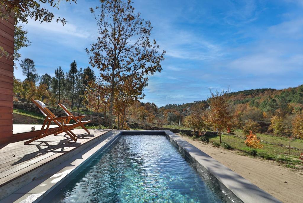 a swimming pool with a bench on a deck at Encosta do Sobreiro - Serra da Estrela in Fornos de Algodres