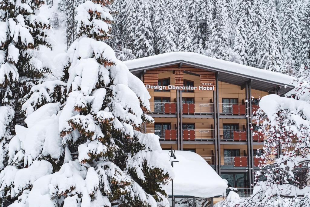 a building with snow covered trees in front of it at Design Oberosler Hotel in Madonna di Campiglio