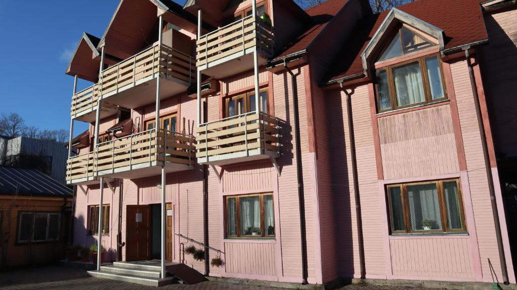 Excelsior Guesthouse في يورمالا: مبنى وردي عليه شرفات خشبية