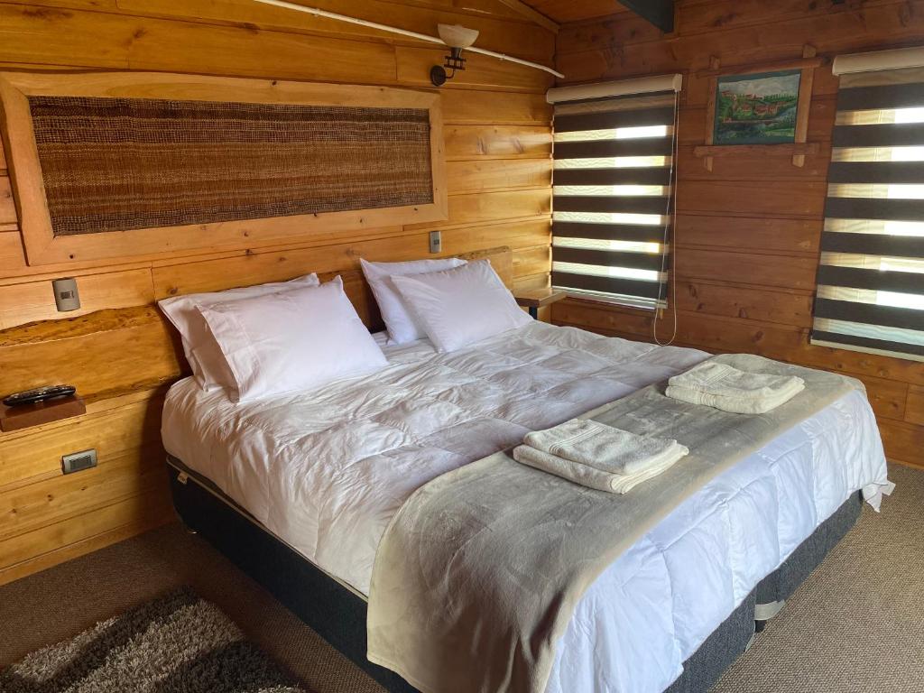 ein Schlafzimmer mit einem Bett in einer Holzhütte in der Unterkunft Hostal Caulle in Río Bueno