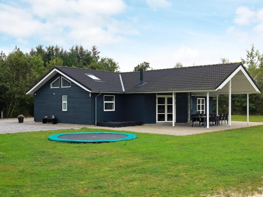 ein blaues Haus mit einem Trampolin im Hof in der Unterkunft 14 person holiday home in H jslev in Bøstrup
