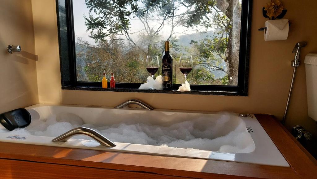 a sink with two glasses of wine and a window at Casa do Alto Santa Mônica- Natureza ao seu redor in Itaipava