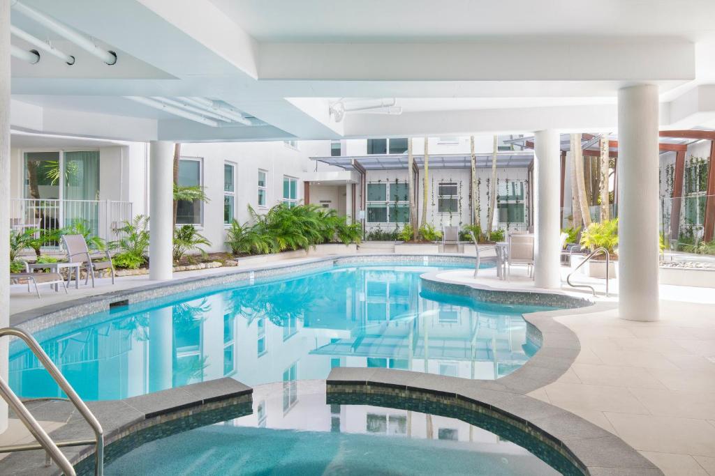 una piscina en un hotel con sillas y mesas en Emerald Noosa, en Noosa Heads