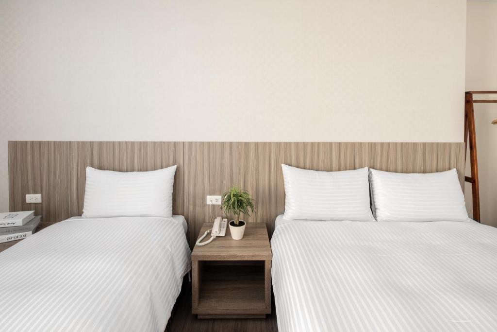 two beds sitting next to each other in a room at Hotel Brown - Chihkan Branch in Tainan