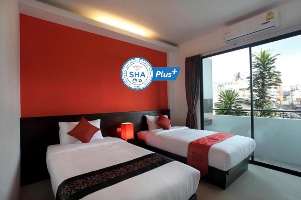 Dos camas en una habitación de hotel con un cartel que dice salta en KARON SINO House, en Karon Beach