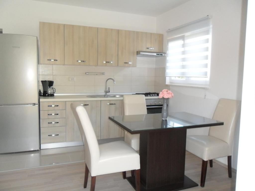 uma cozinha com uma mesa e cadeiras e um frigorífico em Apartments M&M em Grebaštica