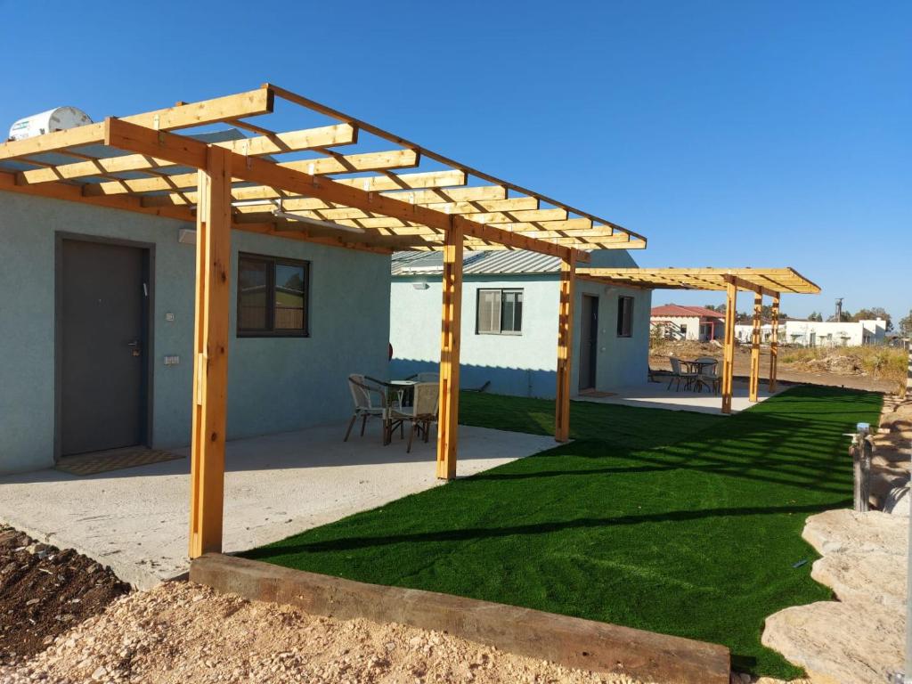 a patio with a wooden pergola and grass at בזלת וגיר in Avnei Eitan