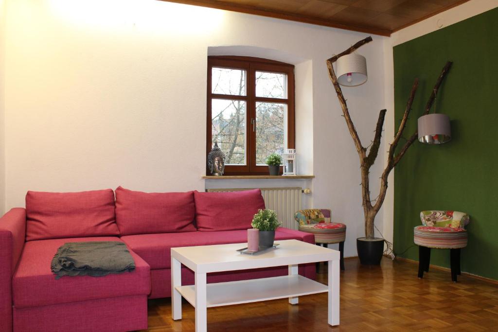 a living room with a red couch and a table at Sandsteinhaus mit Garten im Naturpark Hassberge in Kirchlauter