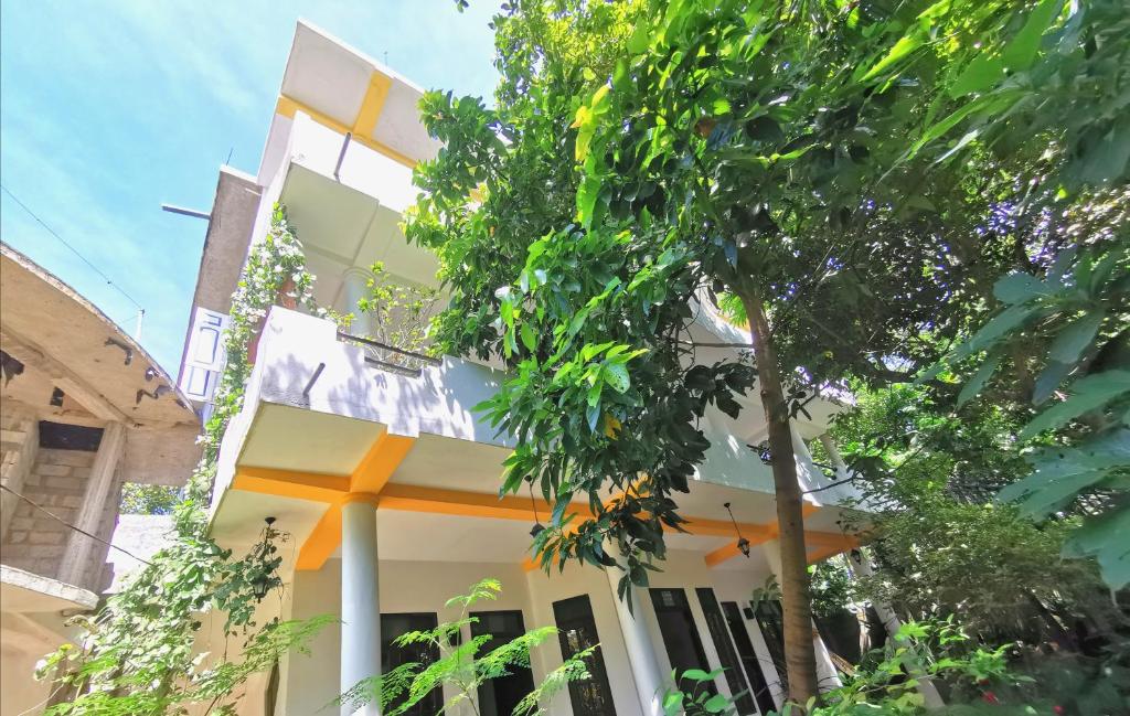 a white and orange building with trees in the foreground at Ramya Villa in Unawatuna