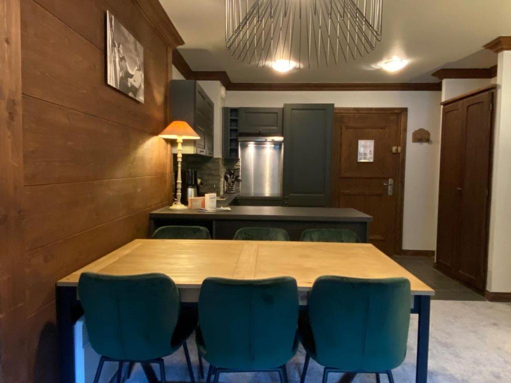 a kitchen with a wooden table and blue chairs at Arc 1950 - Appartement Premium Rénové - Manoir Savoie in Arc 1950