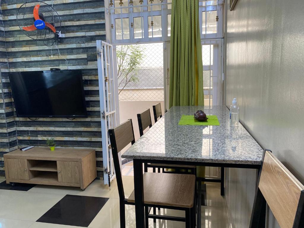 a dining room with a table with chairs and a television at Champs De Mars Apartment in Port Louis