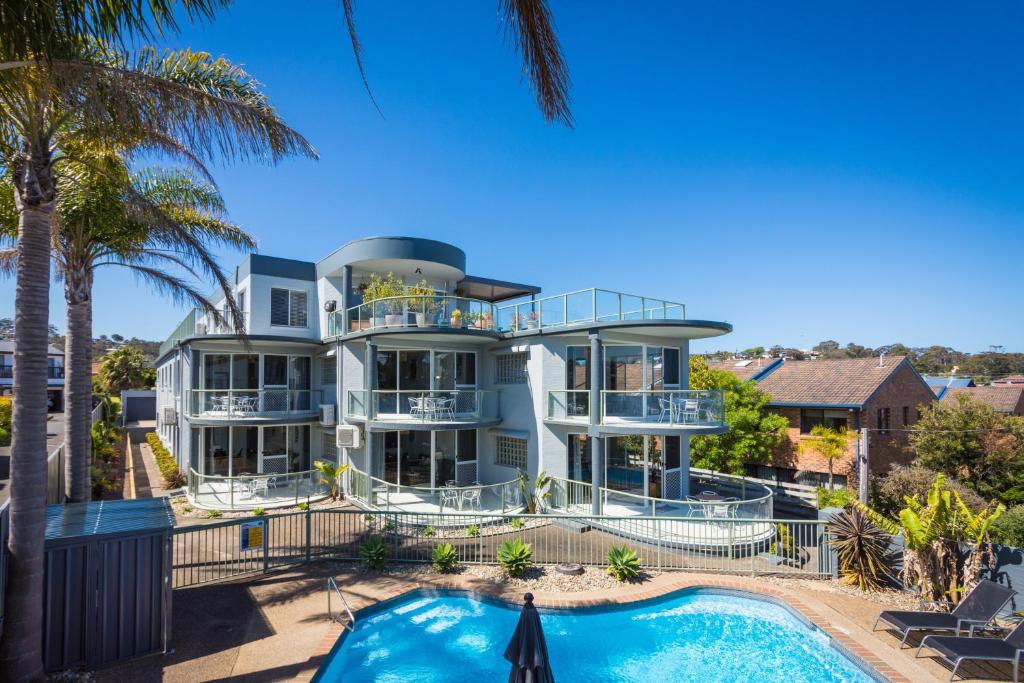 a large white house with a swimming pool at The Palms Apartments in Merimbula