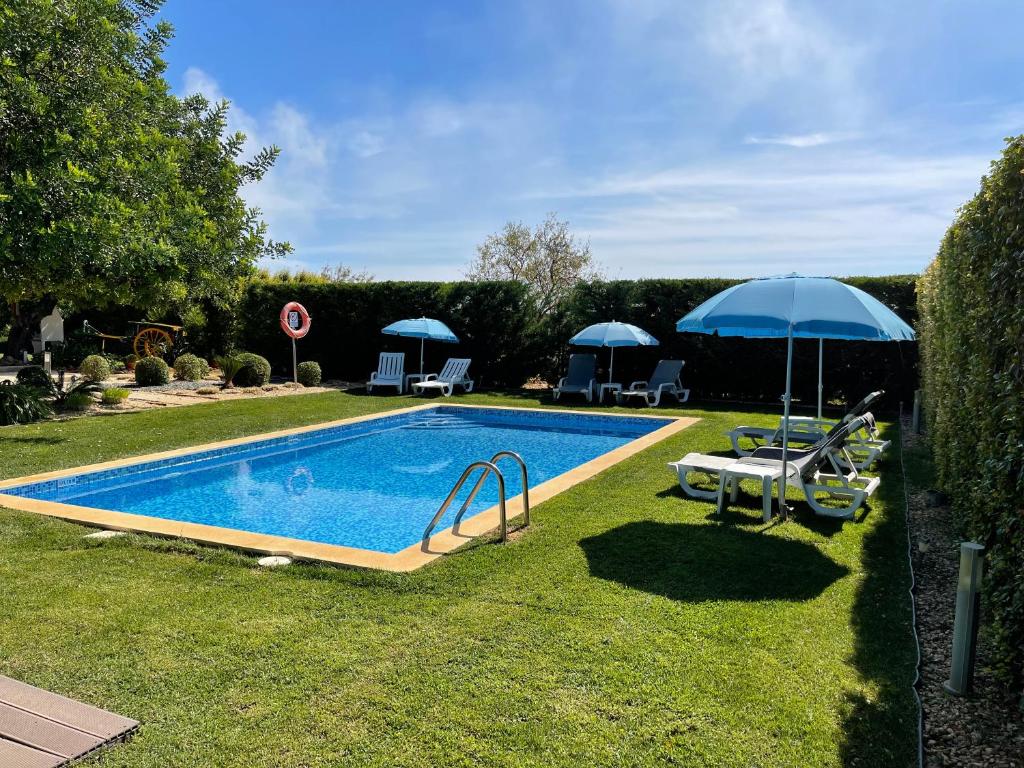 a swimming pool in a yard with an umbrella at Quinta dos Sapos in Silves