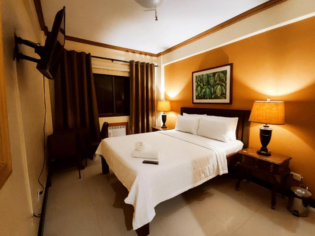 a bedroom with a large white bed and a window at Spring Plaza Hotel in Dasmariñas