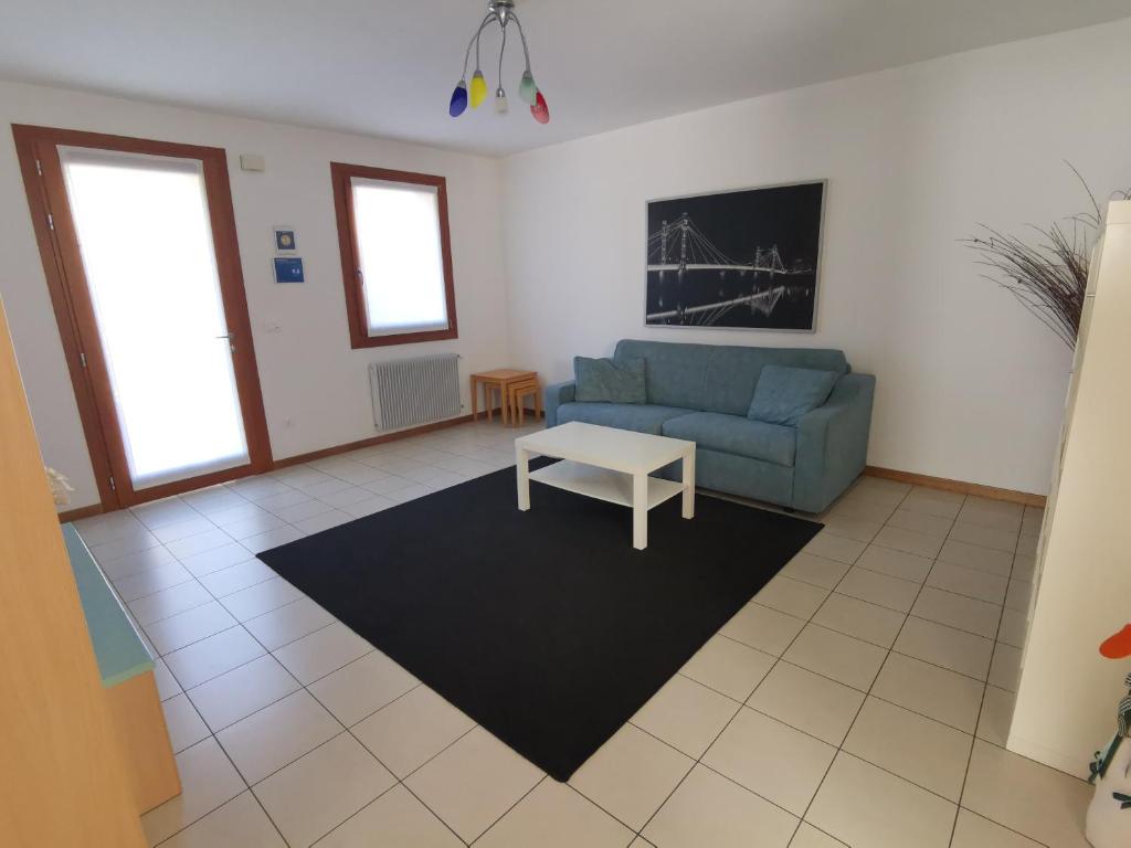- un salon avec un canapé bleu et une table dans l'établissement Cà Maria - Appartamento con Giardino, à San Polo di Piave