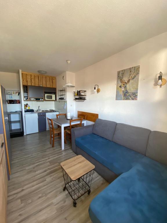 ein Wohnzimmer mit einem blauen Sofa und einer Küche in der Unterkunft Appartement aux pieds des pistes ! in Les Angles