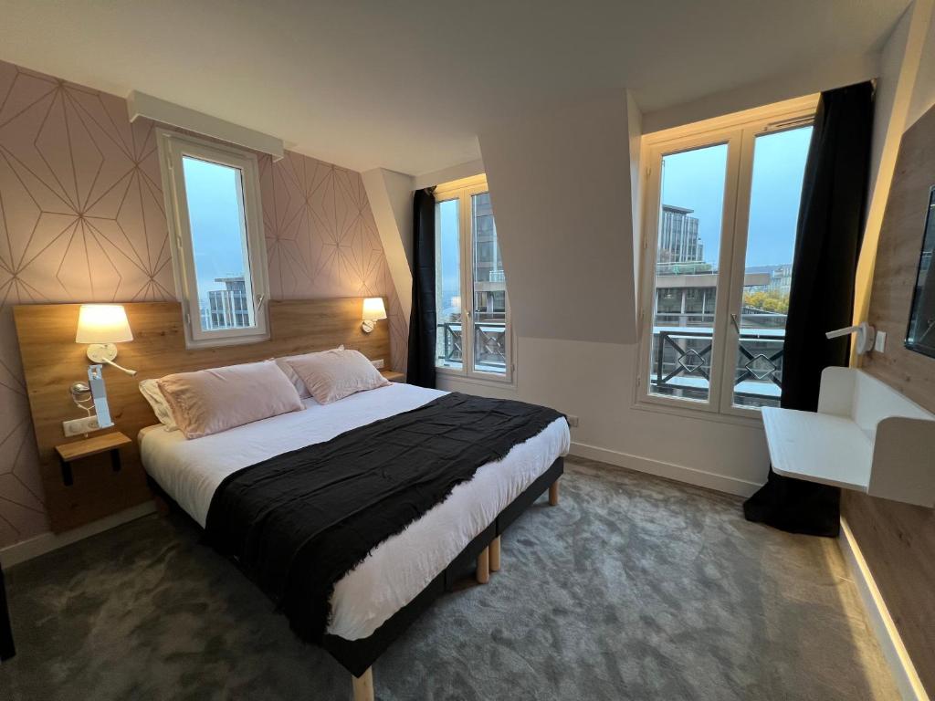 a bedroom with a large bed with two windows at Paris Saint Cloud Hôtel in Saint-Cloud