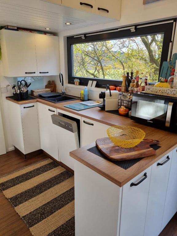 una cucina con mobili bianchi e una grande finestra di Sunset Tiny House GbR a Neuendorf