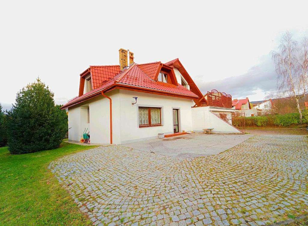 ein weißes Haus mit rotem Dach auf einer Kopfsteinpflasterstraße in der Unterkunft Apartamenty EverySky Kowary - Dom z 5 lub 7 sypialni in Kowary