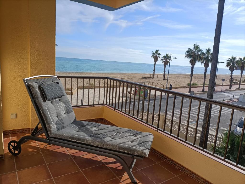 a chair on a balcony with a view of the beach at Apartamento Laurel in Peñíscola