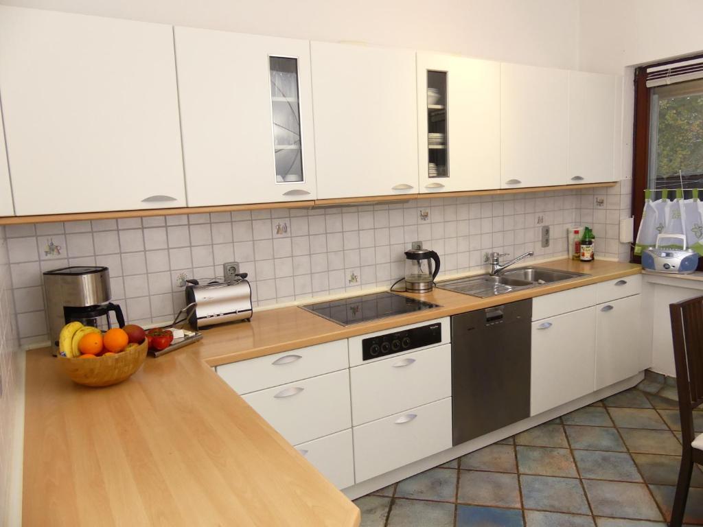 a kitchen with white cabinets and a bowl of fruit on the counter at Ferienhaus Strandlust in Butjadingen