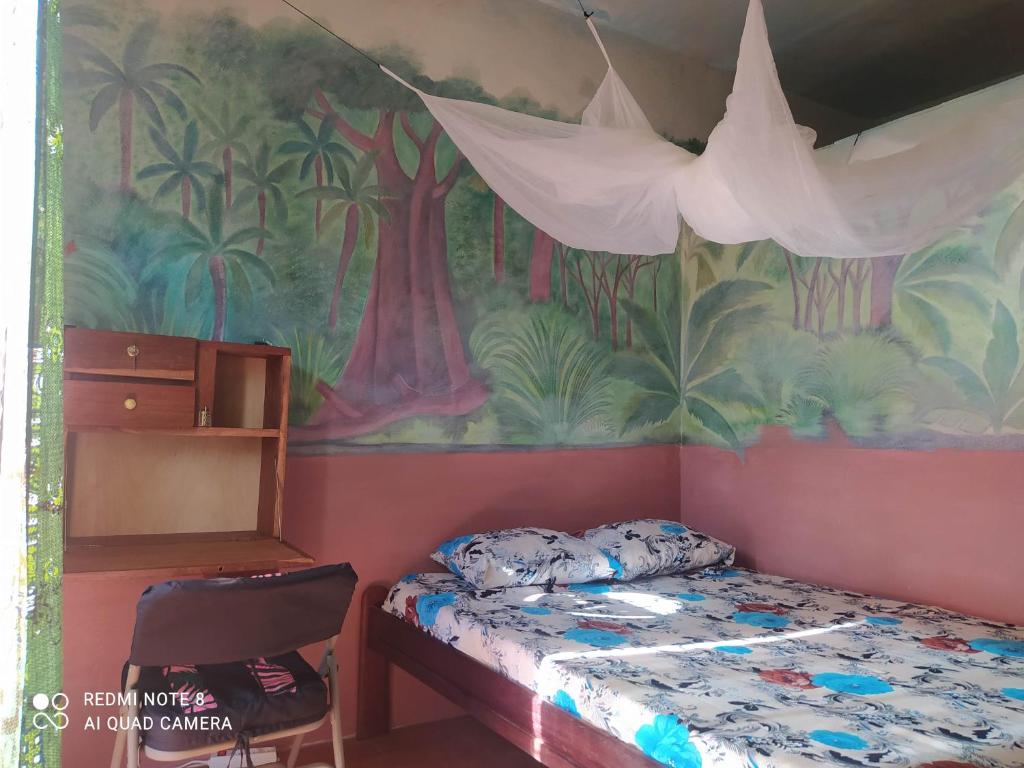 1 dormitorio con 1 cama y una pintura en la pared en Chez Yaya - Chambre Brousse, en Oussouye