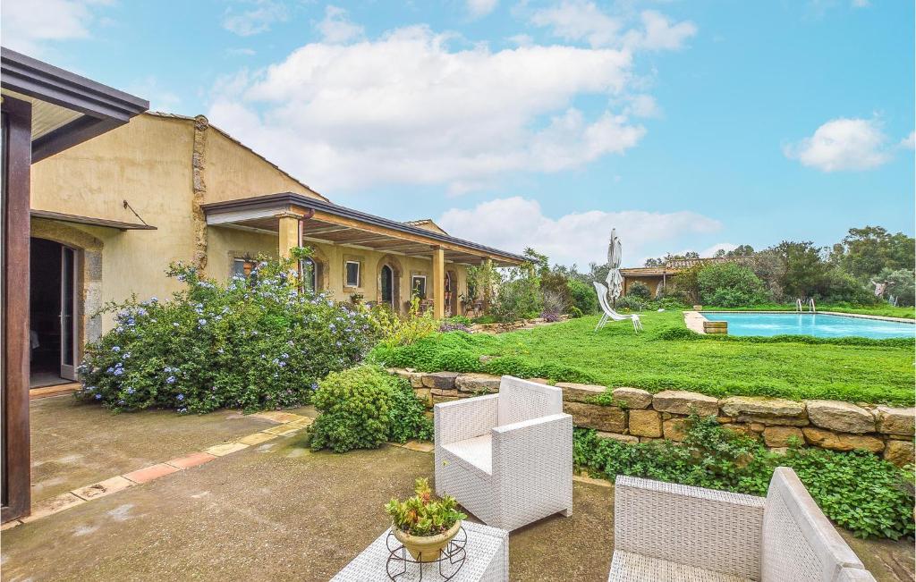 a backyard with two white chairs and a stone wall at Beautiful Home In Caltagirone in Caltagirone