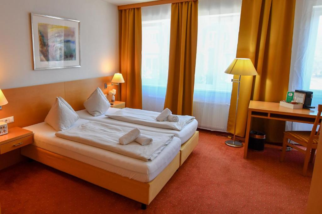 Motel55 - nettes Hotel mit Self Check-In in Villach, Warmbad في فيلاخ: غرفة فندقية بسريرين ومكتب