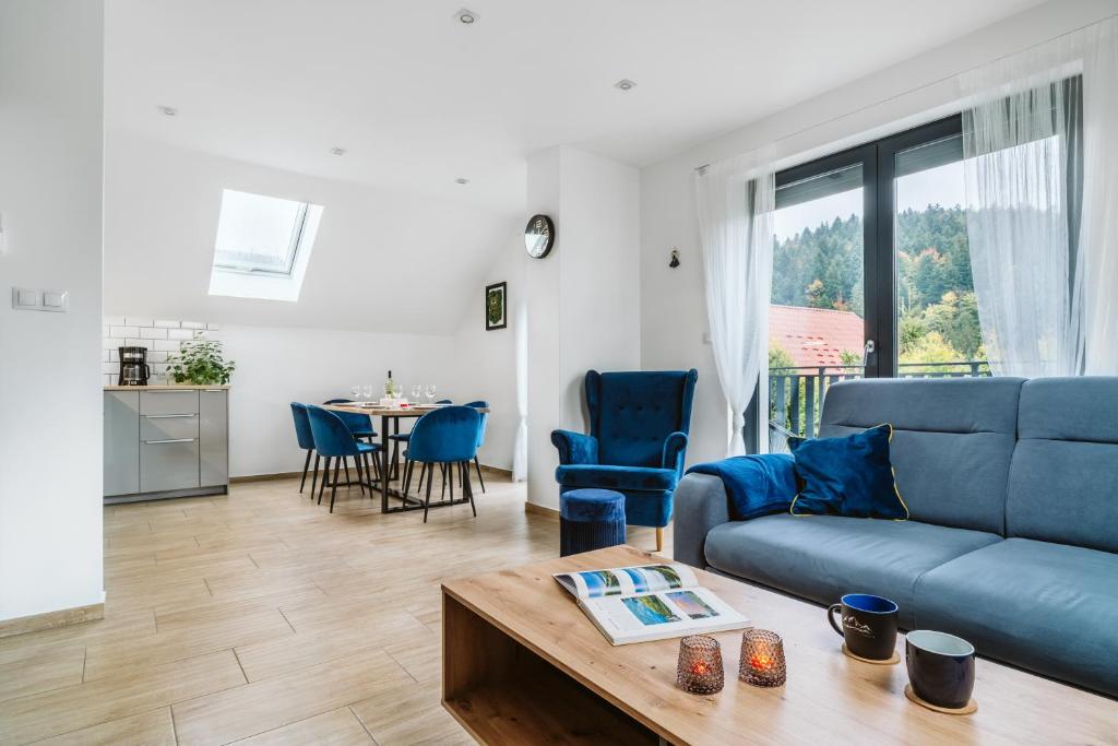 un soggiorno con un divano blu e un tavolo di Apartament Na Borach II SPA a Szczyrk