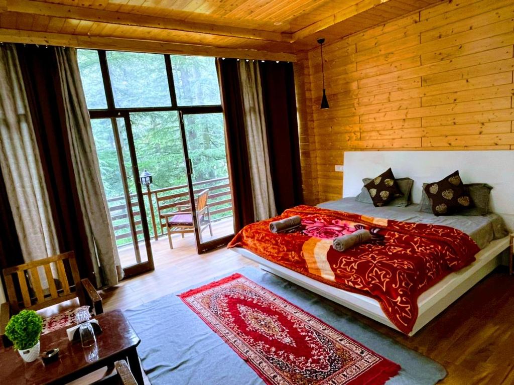a bedroom with a large bed with a red blanket at WildWoodHome Jibhi in Jibhi