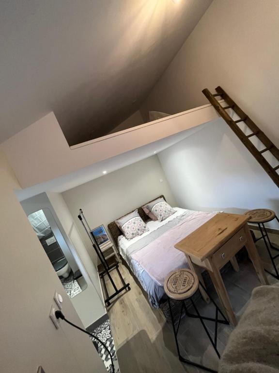 ein kleines Schlafzimmer mit einem Bett und einem Holztisch in der Unterkunft Chambre Folle Avoine in Brié-et-Angonnes