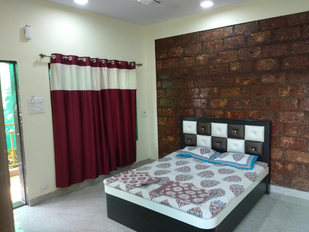 um quarto com uma cama e uma parede de tijolos em Aamantran Residency em Dapoli