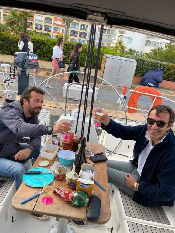 two men sitting at a table on a boat at SUPERBE VOILIER CAP AGDE avec parking gratuit sur place in Cap d&#39;Agde