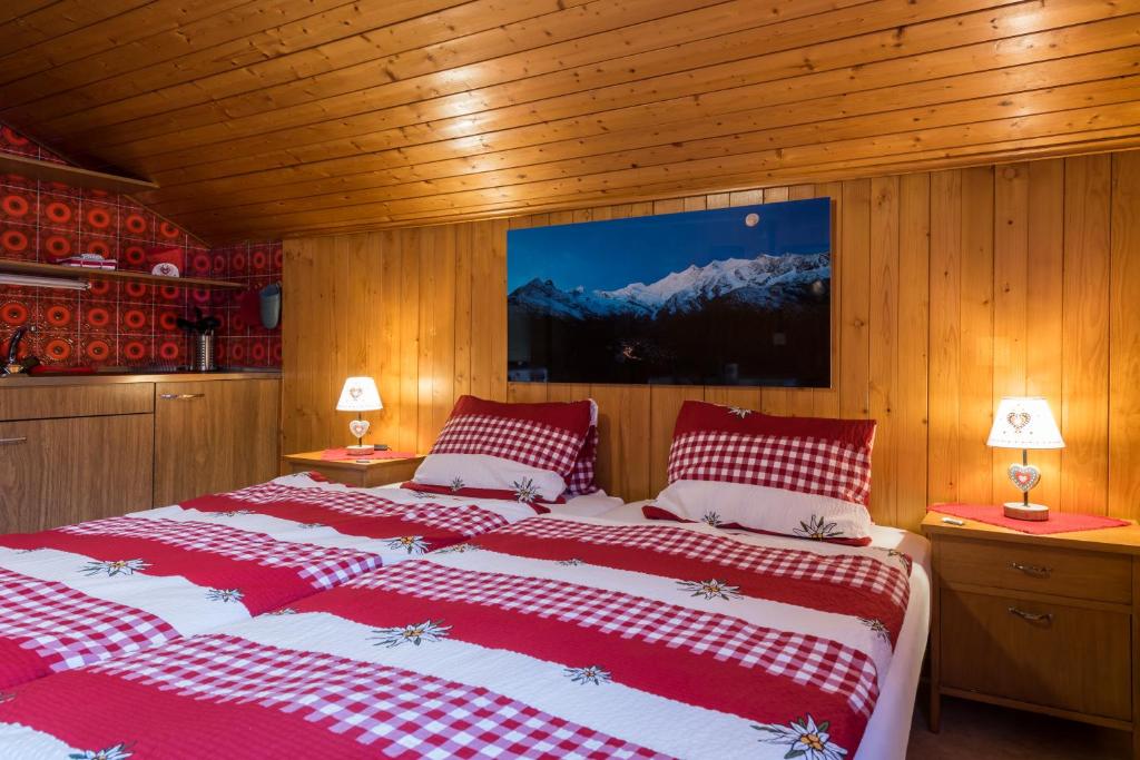 a bedroom with two beds with red and white sheets at Haus Alpenblick in Saas-Grund
