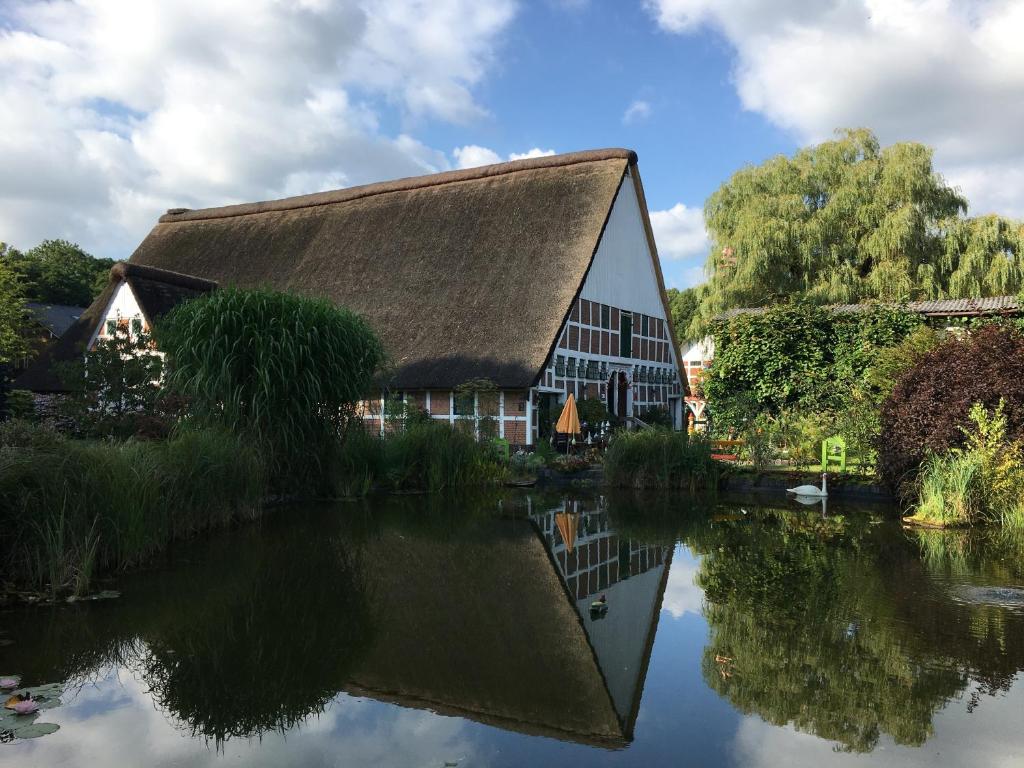 athatched building with its reflection in the water at Taubenhof - Gut Cadenberge in Cadenberge