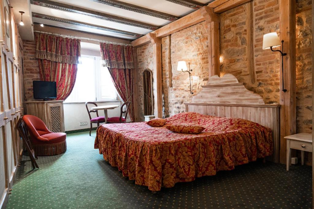 
a hotel room with a bed, chair, and nightstand at Hotel Saint-Martin in Colmar
