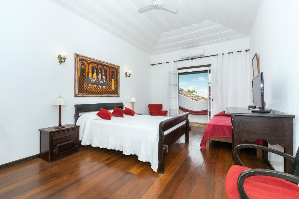1 dormitorio con cama blanca y almohadas rojas en Pousada Afrika en Búzios
