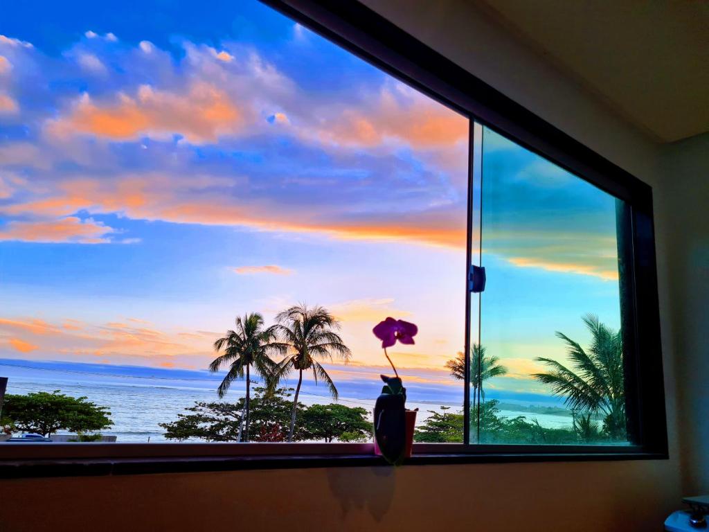 a window with a view of the ocean and palm trees at Apt FRENTE MAR MEAIPE COMPLETO in Guarapari